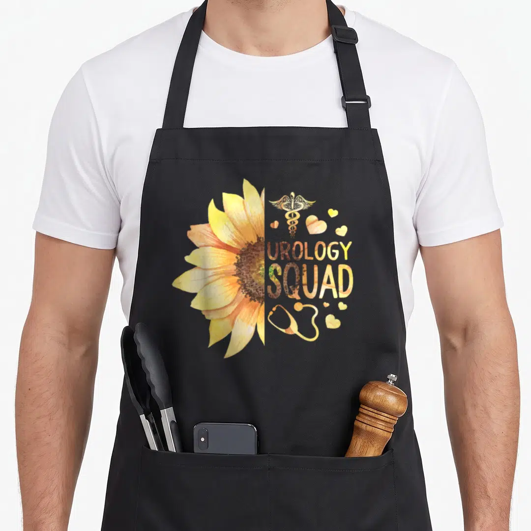 Urology nurse apron - Split sunflower with caduceus, stethoscope, hearts, and UROLOGY SQUAD text in yellow gold brown — shown on a black cotton canvas apron against a white background