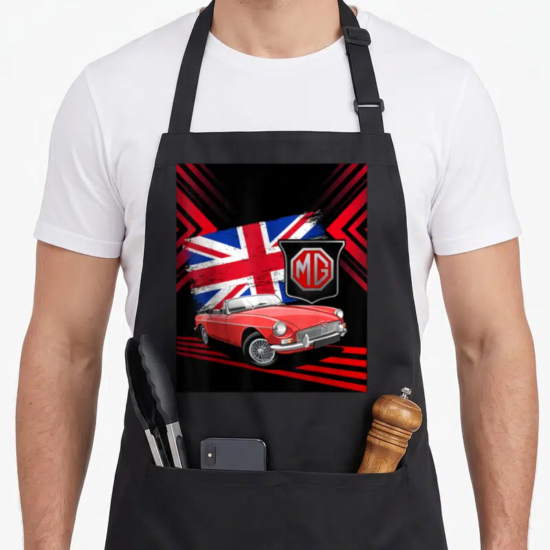Convertible car apron - Red MG convertible car with distressed flag and shield logo on black background — shown on a black cotton canvas apron against a white background