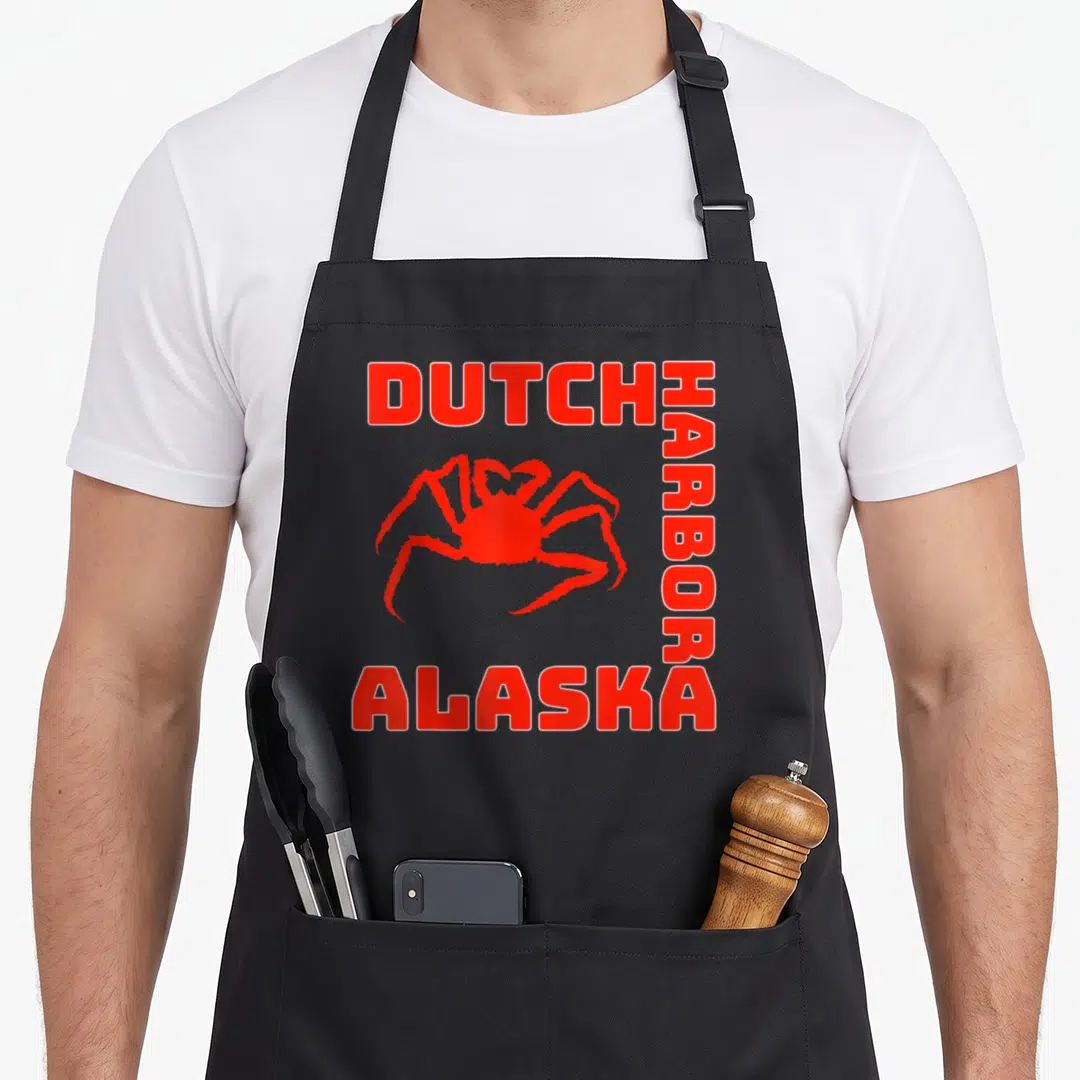 Alaskan dutch apron - Red crab graphic framed by Dutch Harbor Alaska text on black fabric — shown on a black cotton canvas apron against a white background