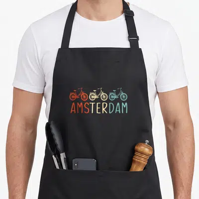 Bike dutch aprons - Three bicycles in red beige and teal above AMSTERDAM text — shown on a black cotton canvas apron against a white background