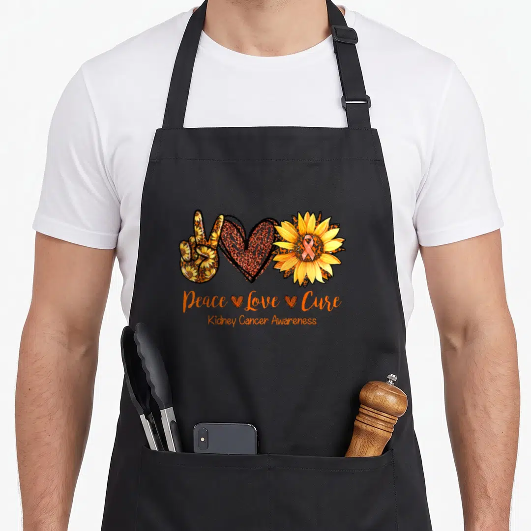 Peace daisy apron - Peace sign heart sunflower with orange yellow brown patterns and awareness text — shown on a black cotton canvas apron against a white background