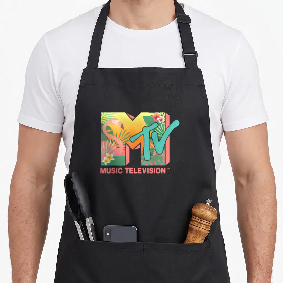 Mtv flamingo apron - MTV logo filled with pink flamingo, green leaves, and yellow flowers, MUSIC TELEVISION text below — shown on a black cotton canvas apron against a white background