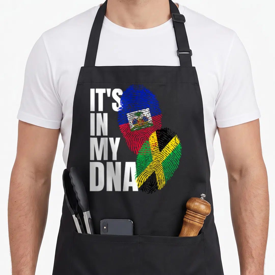 Jamaican haitian heritage aprons - Stacked white text next to two fingerprints filled with Haitian and Jamaican flag — shown on a black cotton canvas apron against a white background