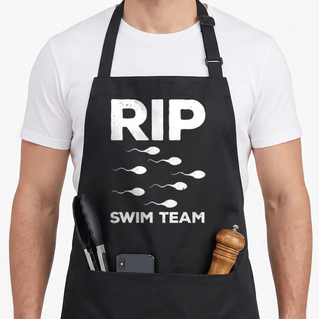 Rip makers apron - White distressed RIP SWIM TEAM text with seven swimming sperm icons — shown on a black cotton canvas apron against a white background