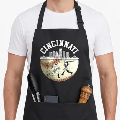 Cincinnati player baseball apron - White Cincinnati text over skyline and two players on a distressed red-stitched — shown on a black cotton canvas apron against a white background