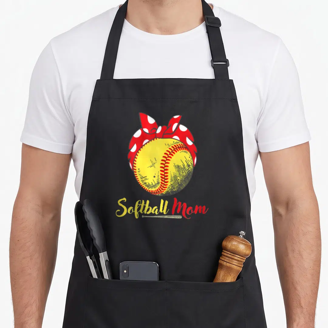 Flag mother's day aprons - Yellow softball with red and white polka dot bow and Softball Mom script text — shown on a black cotton canvas apron against a white background