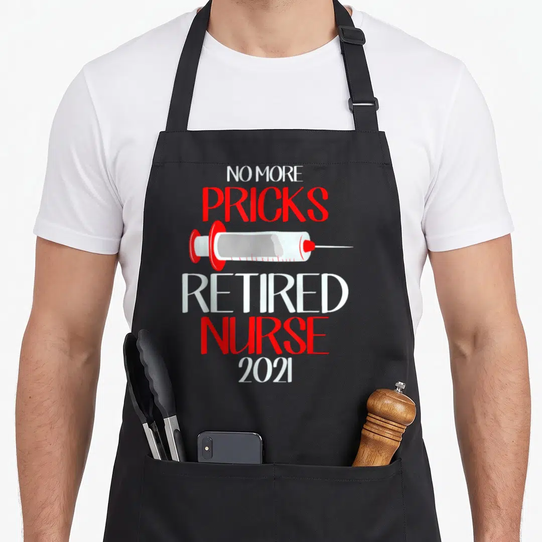 Nursing funny retirement aprons - Syringe between No More Pricks and Retired Nurse 2021 text in white red grey — shown on a black cotton canvas apron against a white background