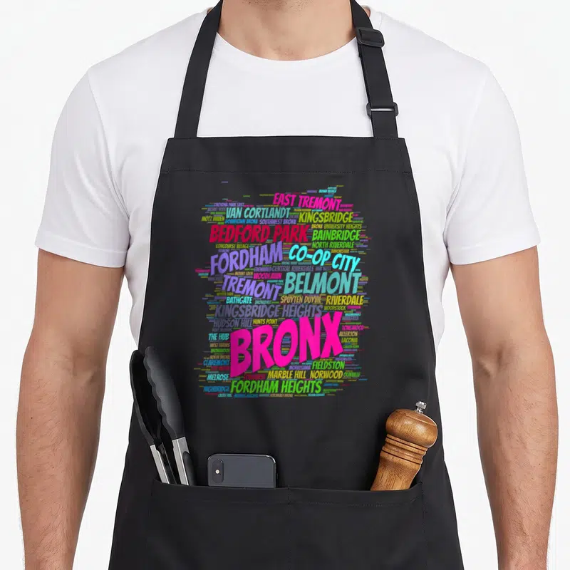 Boogie new york apron - Colorful word cloud of Bronx neighborhoods like Fordham and Riverdale with large pink BRONX — shown on a black cotton canvas apron against a white background