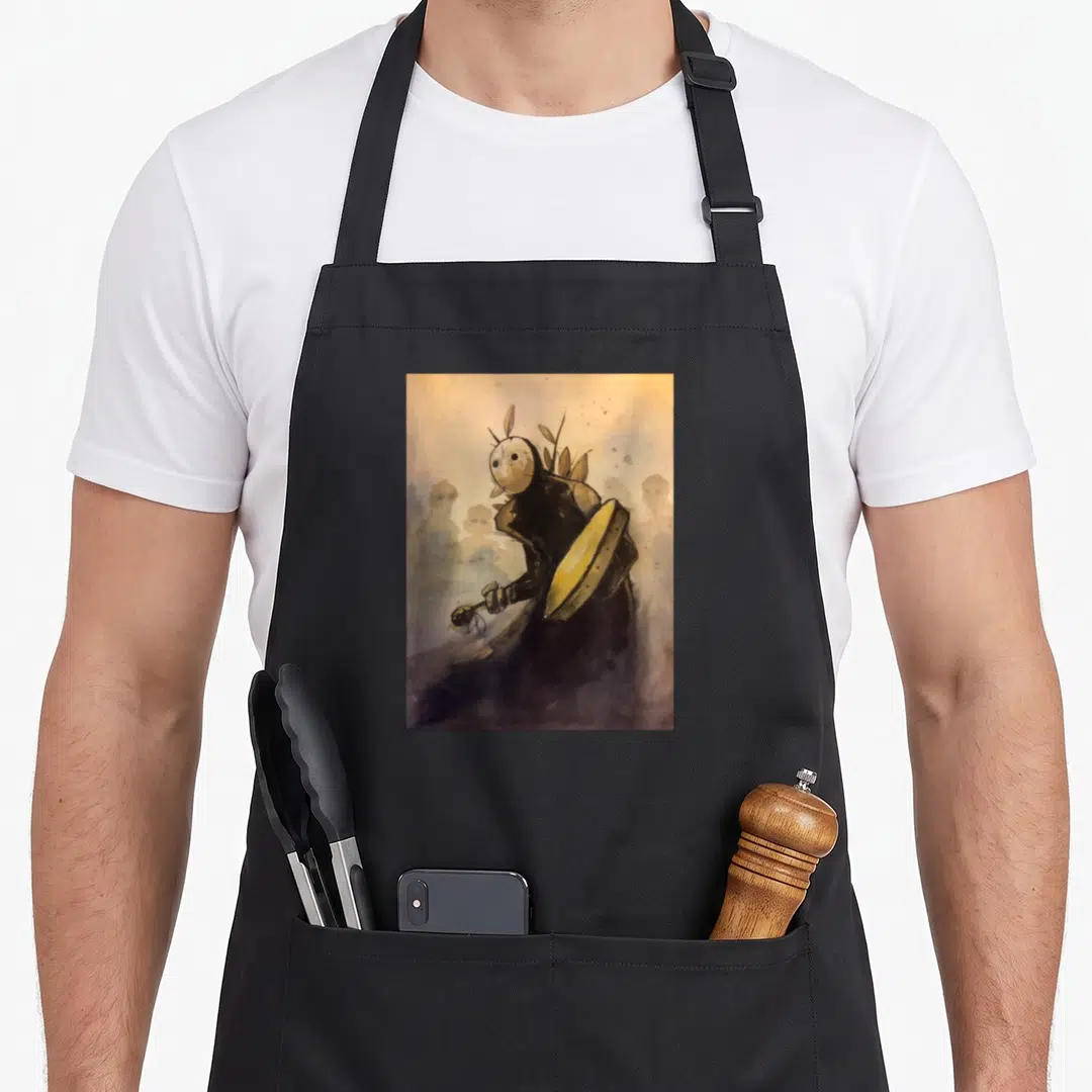 Shaman tides apron - Watercolor masked character holding yellow shield and rattle against grey hazy background — shown on a black cotton canvas apron against a white background