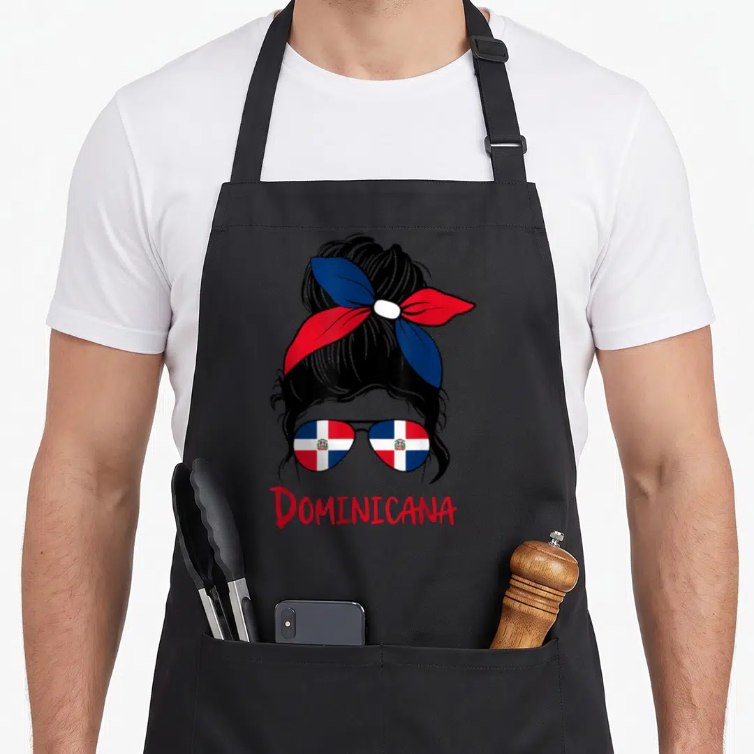 Dominican messy aprons - Woman silhouette with bun, flag sunglasses, and red DOMINICANA text — shown on a black cotton canvas apron against a white background