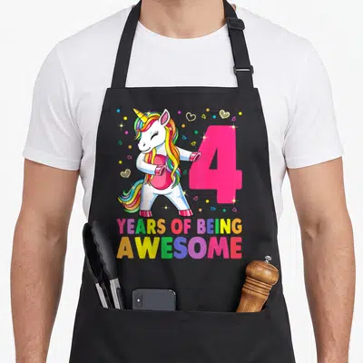 Unicorn flossing birthday apron - Cartoon unicorn dabbing next to pink number 4 and colorful YEARS OF BEING AWESOME text — shown on a black cotton canvas apron against a white background