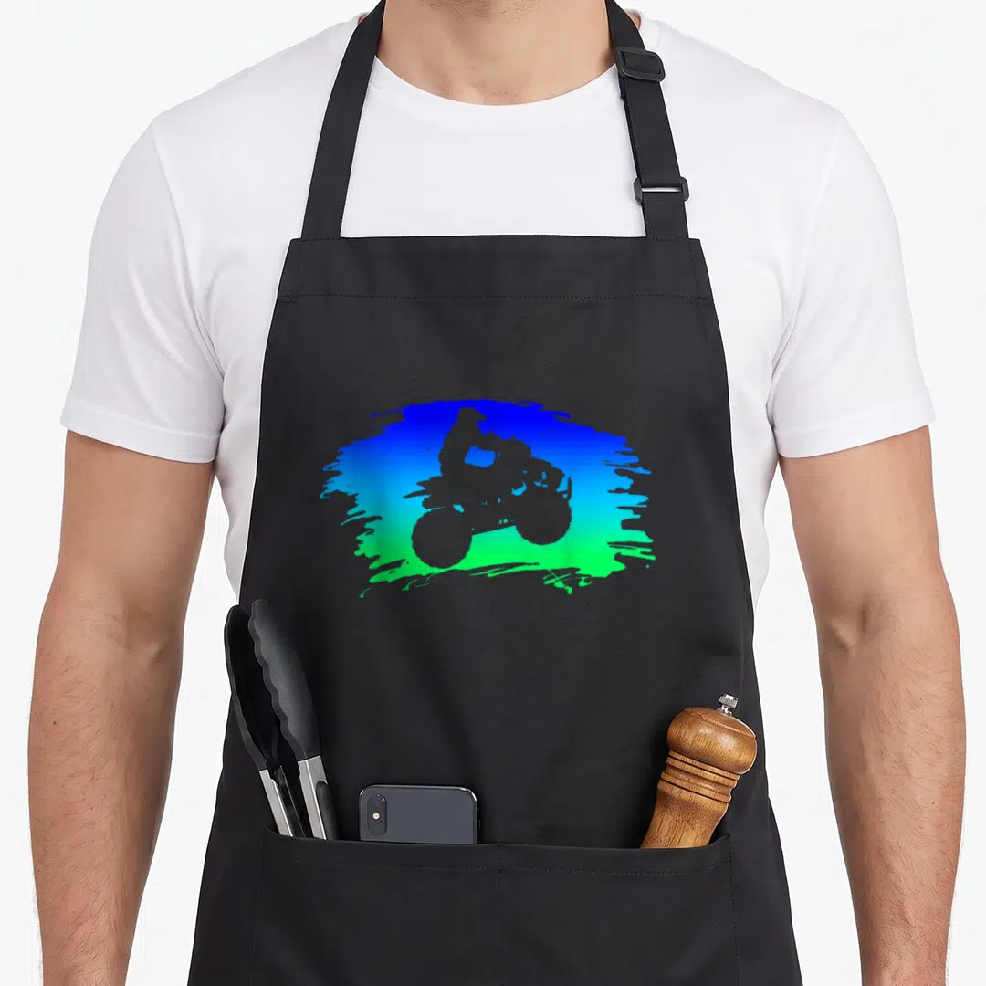 Quad wheel apron - White ATV rider silhouette inside blue to green gradient paint splash — shown on a black cotton canvas apron against a white background
