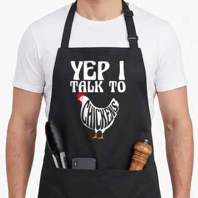 Retro farmer animal chicken apron - Cartoon chicken with YEP I TALK TO CHICKENS text inside body — shown on a black cotton canvas apron against a white background