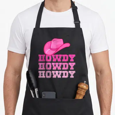 Howdy western apron - Pink cartoon cowboy hat above three stacked rows of HOWDY text in western font — shown on a black cotton canvas apron against a white background