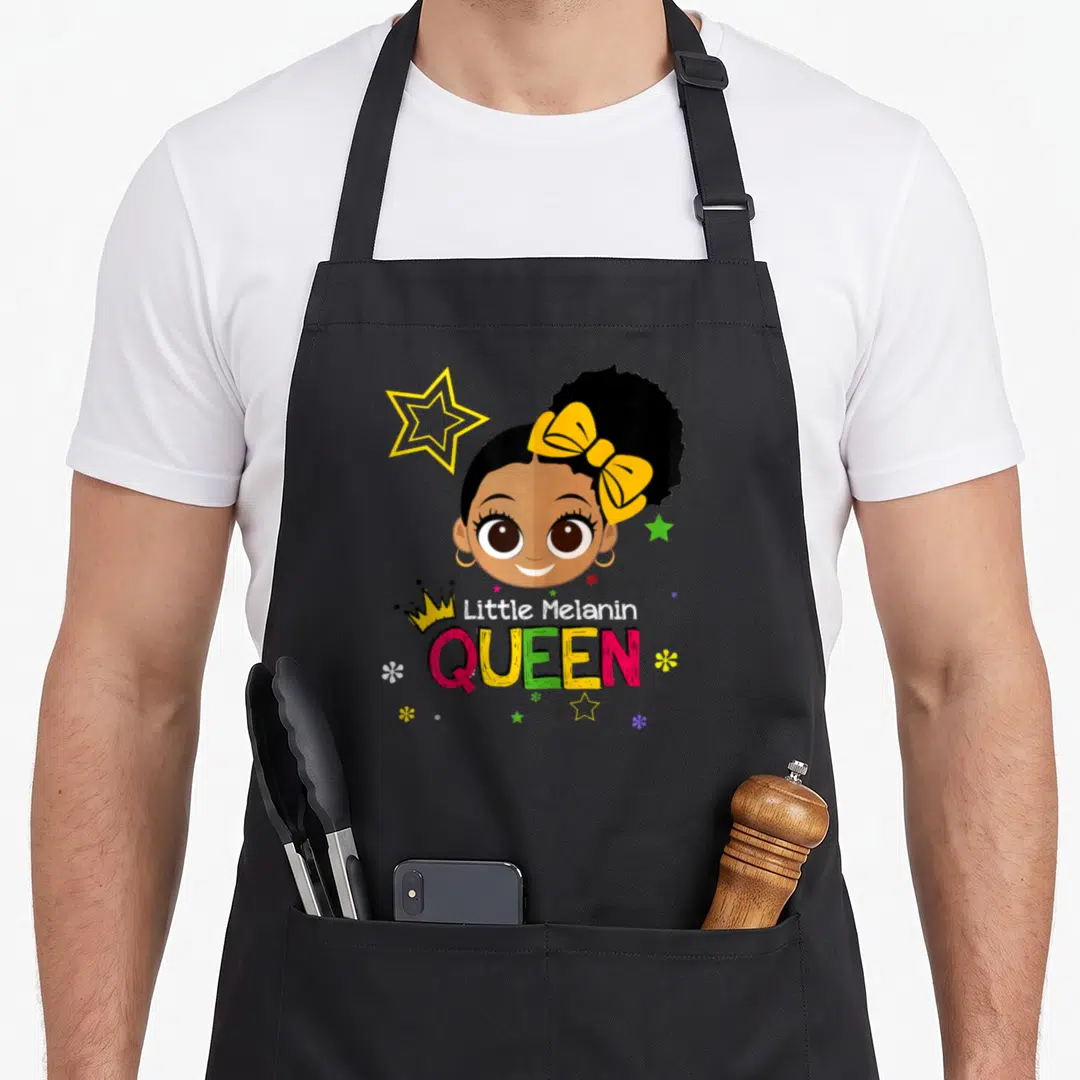 Melanin queen apron - Cartoon girl with yellow bow and crown, text Little Melanin QUEEN surrounded by stars — shown on a black cotton canvas apron against a white background