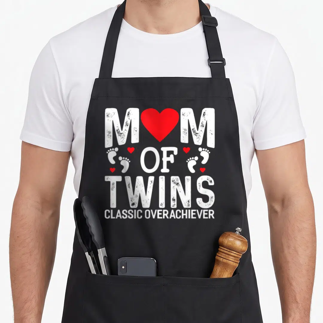 Twin emu mom apron - MOM OF TWINS text with red heart and baby footprints — shown on a black cotton canvas apron against a white background
