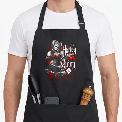 Arkham vehicle apron - Harley Quinn portrait with dice and stacked text over red white diamond pattern — shown on a black cotton canvas apron against a white background