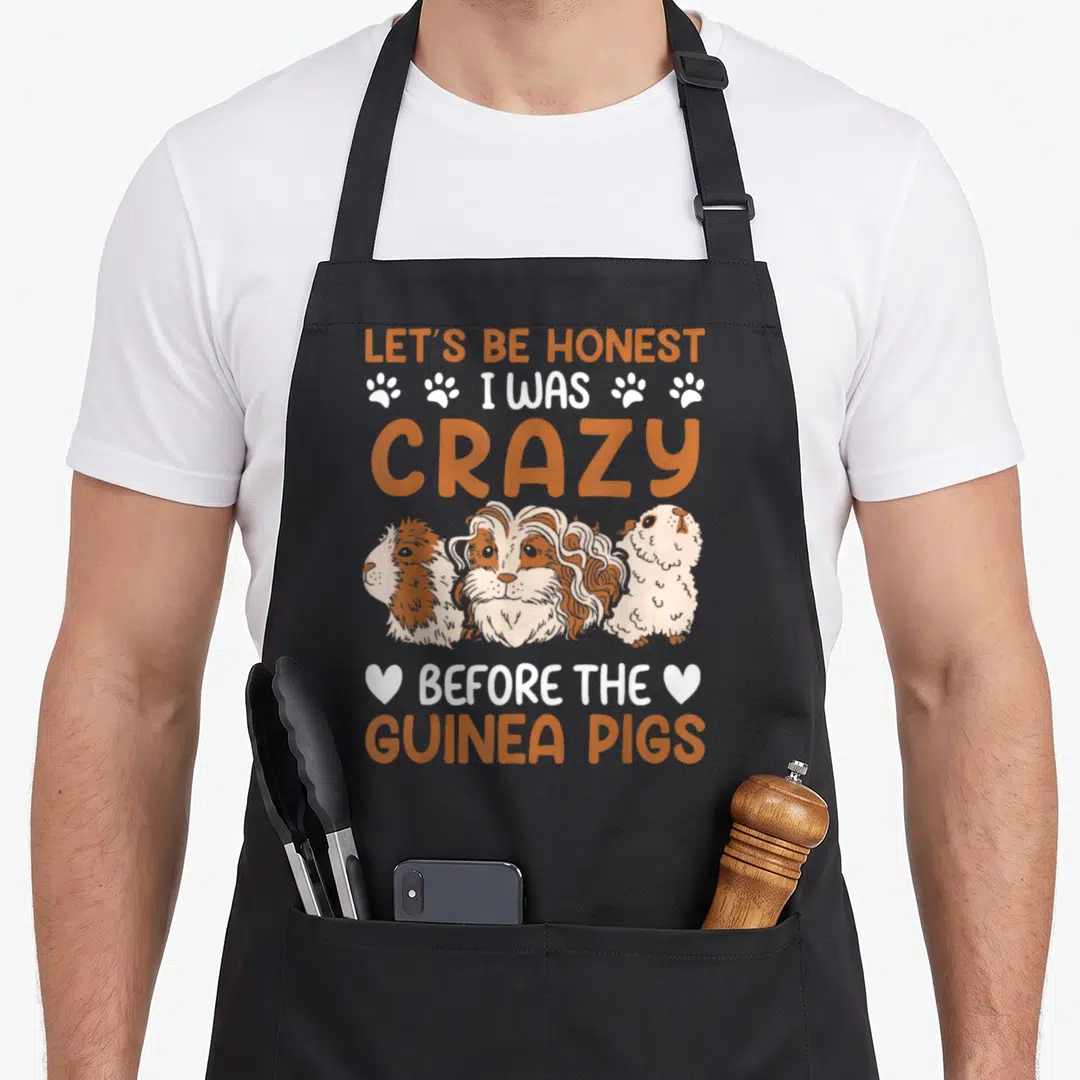 Rodent crazy guinea lady apron - Stacked text reading Let's Be Honest I Was Crazy Before The Guinea Pigs above three — shown on a black cotton canvas apron against a white background