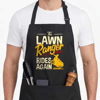 Lawn rangers apron - Stacked text The LAWN Ranger RIDES AGAIN with yellow mower rider silhouette and red swoosh line — shown on a black cotton canvas apron against a white background