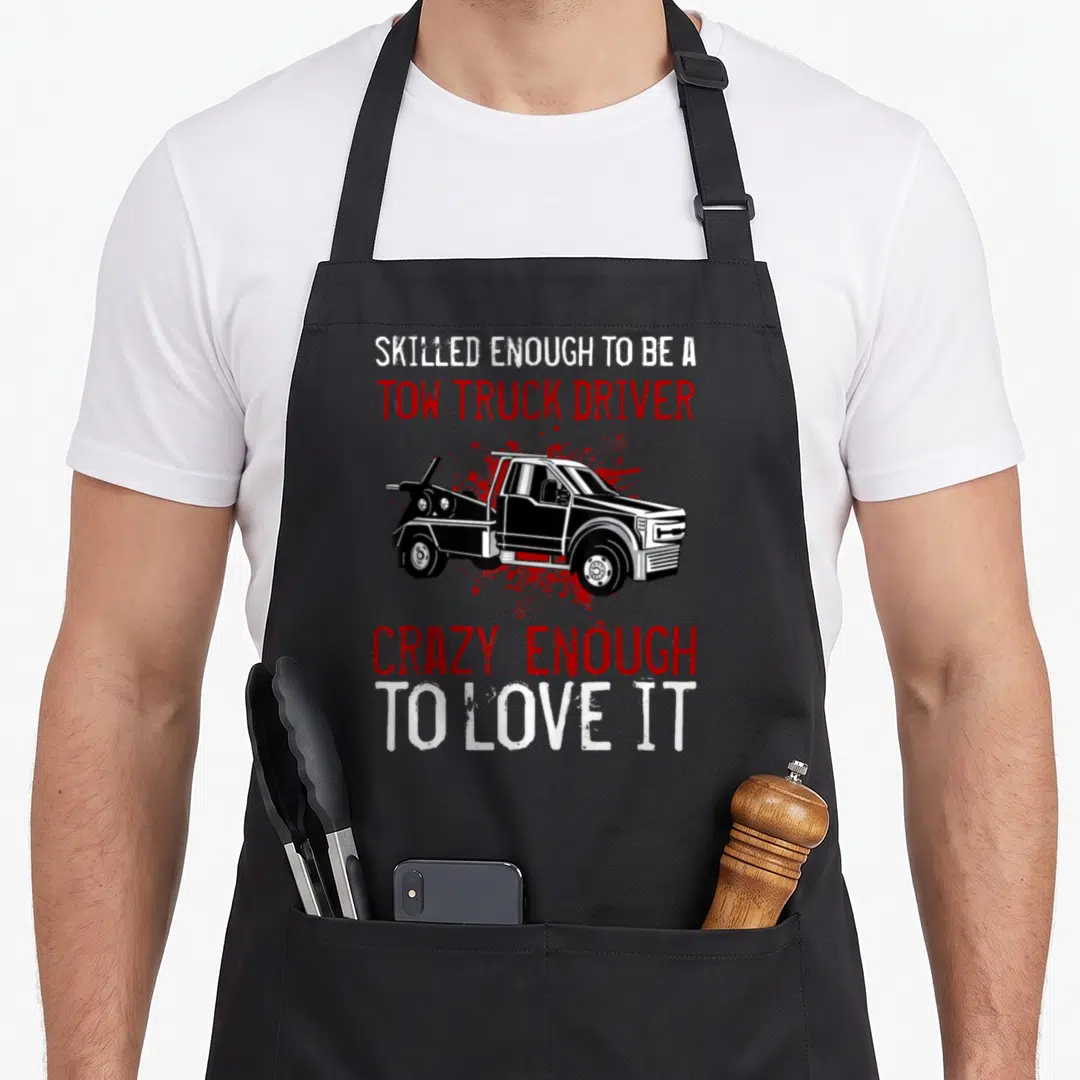 Recovery truck apron - Tow truck graphic with white and red distressed text reading Skilled Enough To Be A Tow Truck — shown on a black cotton canvas apron against a white background