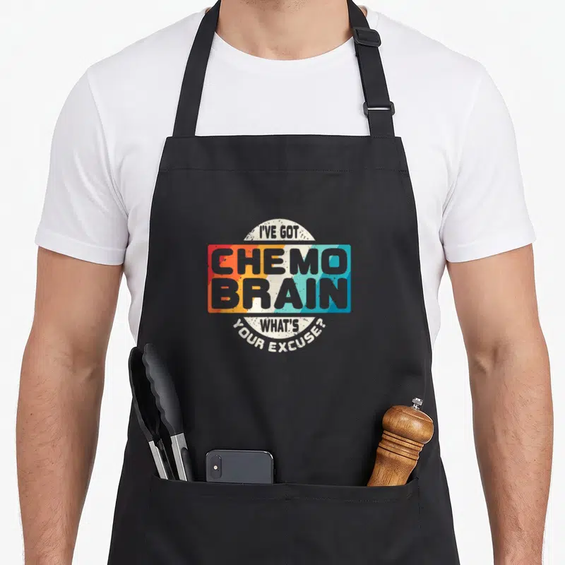 Cancer chemo warrior apron - Retro stacked text design reading I've Got Chemo Brain What's Your Excuse in orange yellow — shown on a black cotton canvas apron against a white background