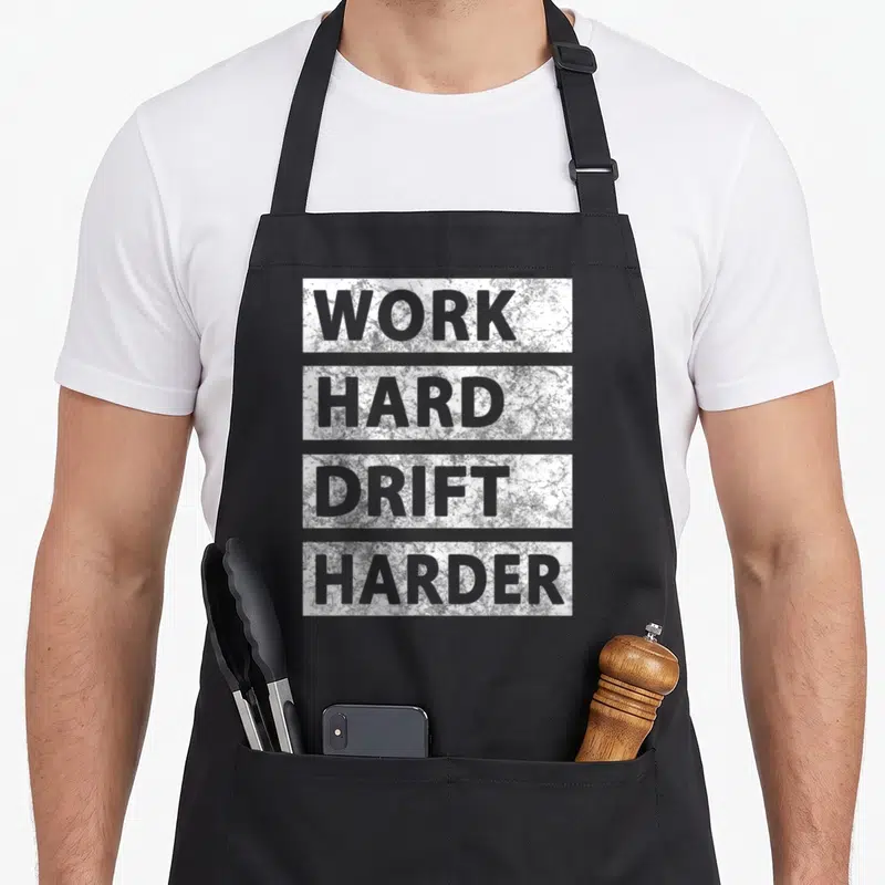 Tokyo car apron - Stacked white distressed text blocks reading Work Hard Drift Harder — shown on a black cotton canvas apron against a white background