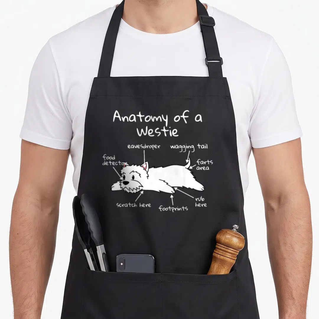 Anatomy westie apron - Cartoon white Westie labeled with eavesdroper, food detector, and farts area text — shown on a black cotton canvas apron against a white background