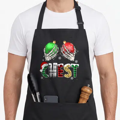 Costume couples christmas aprons - Skeleton hands holding red and green ornaments above patterned CHEST text with Santa — shown on a black cotton canvas apron against a white background