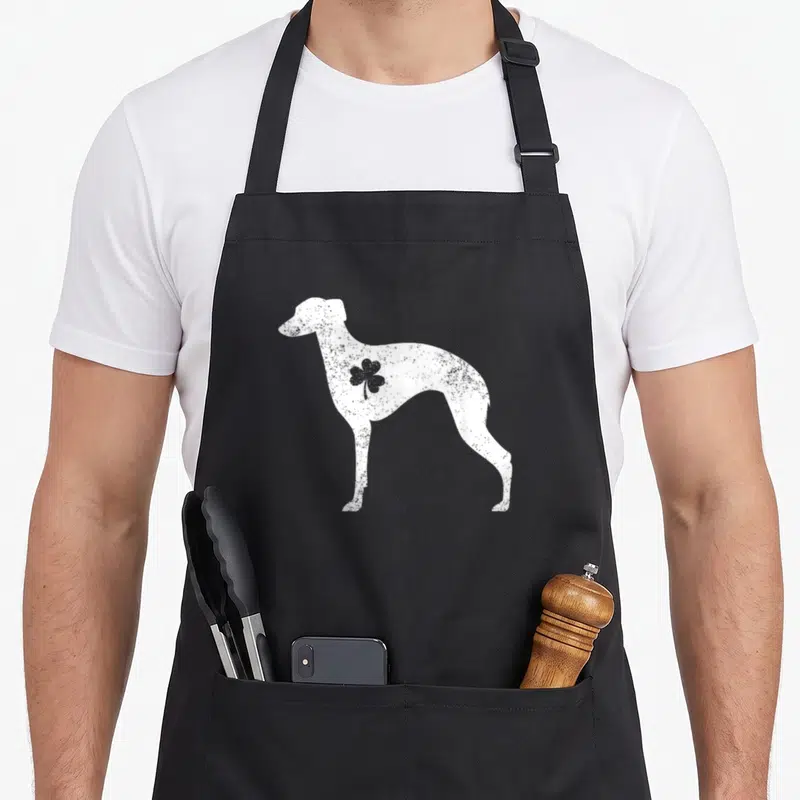 Whippet st patrick day aprons - White distressed whippet silhouette with grey shamrock on shoulder — shown on a black cotton canvas apron against a white background