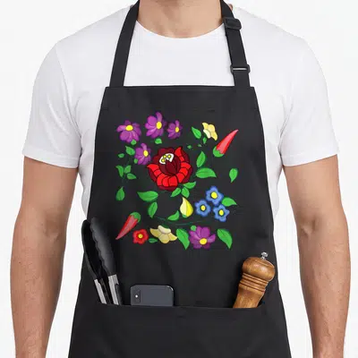 Folk hungarian apron - Red flower wreath with purple blue yellow blooms green leaves and two red chili peppers — shown on a black cotton canvas apron against a white background