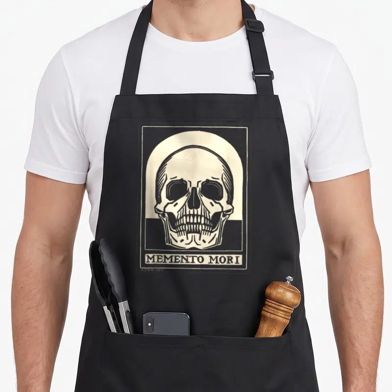 Stoic phd student apron - Grey and cream line art skull inside arch with Memento Mori text below — shown on a black cotton canvas apron against a white background