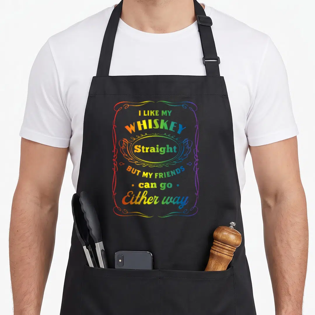 Whiskey friends apron - Rainbow gradient text reading I like my whiskey straight inside ornamental frame — shown on a black cotton canvas apron against a white background