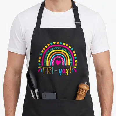 Fri yay teacher apron - Cartoon rainbow with pink heart and FRI=yay text in multiple colors — shown on a black cotton canvas apron against a white background
