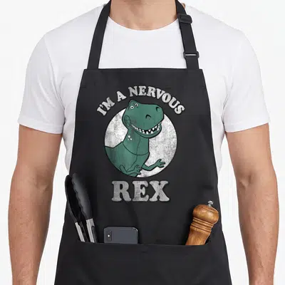 Nervous t-rex apron - Green T-Rex inside white circle with arched text I'M A NERVOUS REX below — shown on a black cotton canvas apron against a white background