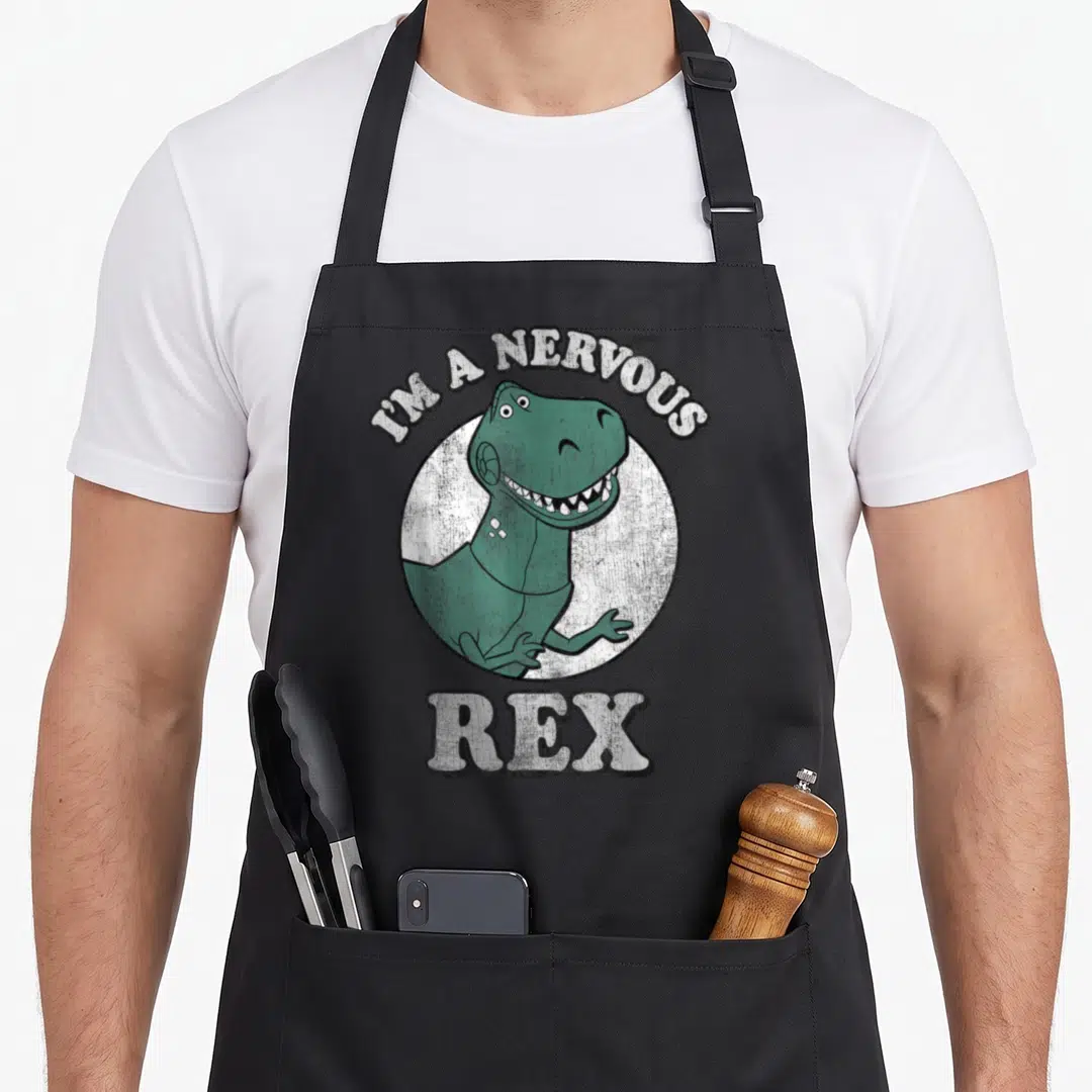 Nervous t-rex apron - Green T-Rex inside white circle with arched text I'M A NERVOUS REX below — shown on a black cotton canvas apron against a white background