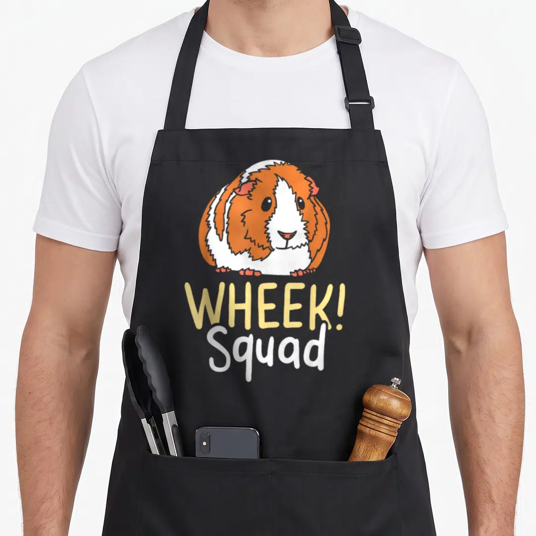 Funny pig best guinea apron - Cartoon guinea pig in orange and white above yellow Wheek and white Squad text — shown on a black cotton canvas apron against a white background