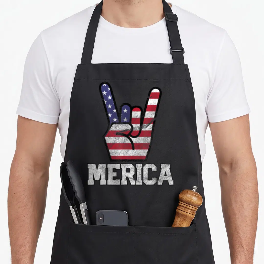 Merica 4th of july apron - Distressed hand gesture filled with red white blue flag stripes above MERICA text — shown on a black cotton canvas apron against a white background