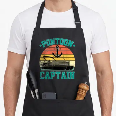 Pontoon driving apron - Retro PONTOON CAPTAIN text with boat and anchor on striped orange yellow background — shown on a black cotton canvas apron against a white background
