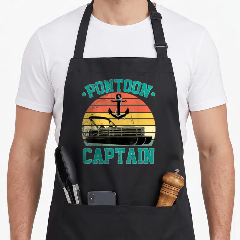 Pontoon driving apron - Retro PONTOON CAPTAIN text with boat and anchor on striped orange yellow background — shown on a black cotton canvas apron against a white background