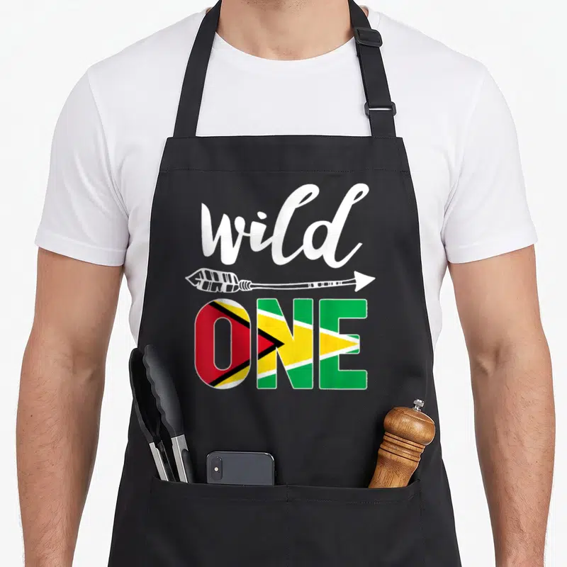 Guyana birthday apron - Wild ONE text with arrow and Guyana flag pattern fill — shown on a black cotton canvas apron against a white background