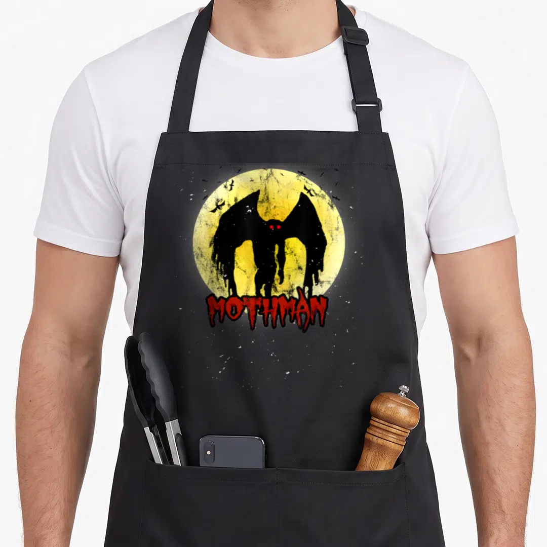 Moon bat apron - Black Mothman silhouette before yellow moon with red MOTHMAN text and small bats — shown on a black cotton canvas apron against a white background