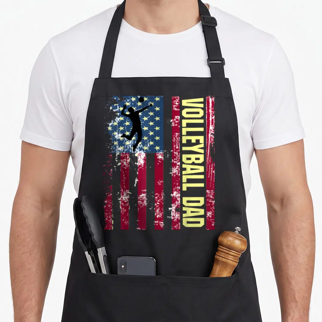 Funny volleyball american flag apron - Vertical distressed US flag with black volleyball player silhouette and yellow — shown on a black cotton canvas apron against a white background