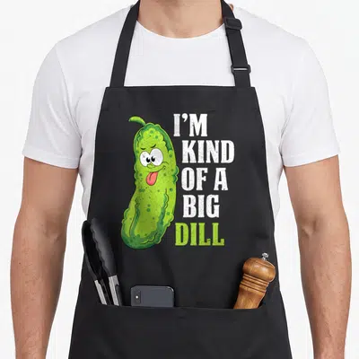 Cucumber dill pickle apron - Cartoon pickle with I'M KIND OF A BIG DILL text in white and lime green — shown on a black cotton canvas apron against a white background