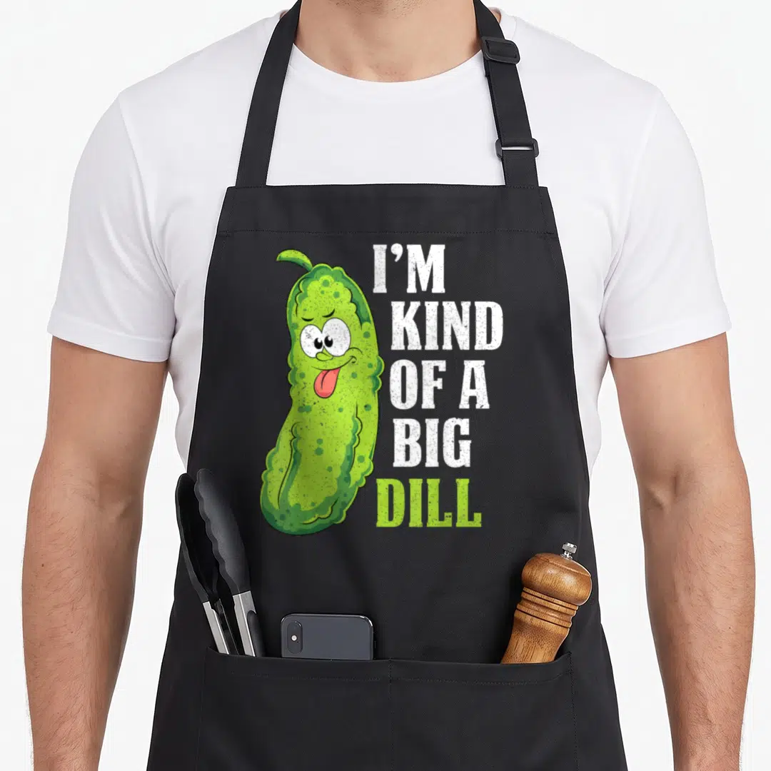 Cucumber dill pickle apron - Cartoon pickle with I'M KIND OF A BIG DILL text in white and lime green — shown on a black cotton canvas apron against a white background