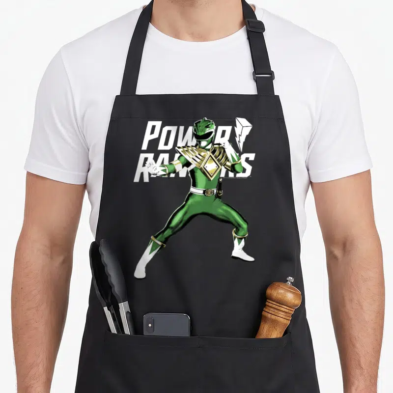 Action karate apron - Green Power Ranger standing pose with white power rangers text and gold accents — shown on a black cotton canvas apron against a white background