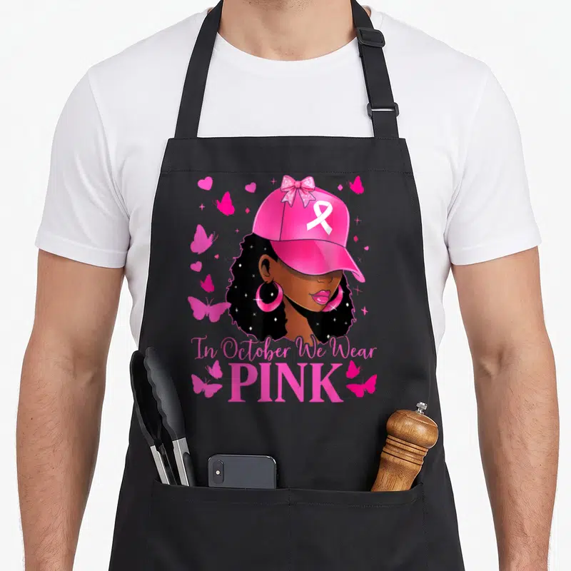 Retro october breast cancer awareness aprons - Cartoon woman in pink cap with ribbon surrounded by pink butterflies — shown on a black cotton canvas apron against a white background