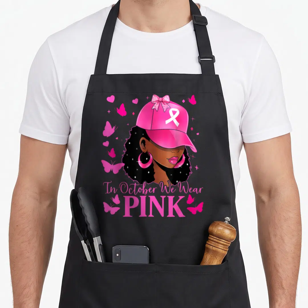 Retro october breast cancer awareness aprons - Cartoon woman in pink cap with ribbon surrounded by pink butterflies — shown on a black cotton canvas apron against a white background