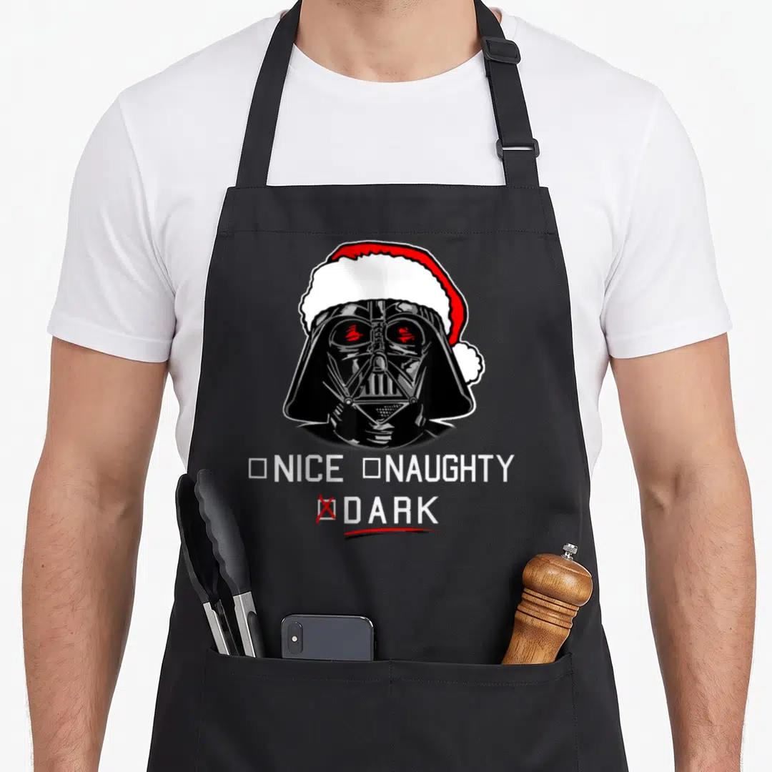 Dark santa apron - Darth Vader in Santa hat with Nice Naughty Dark checklist marked with red X — shown on a black cotton canvas apron against a white background
