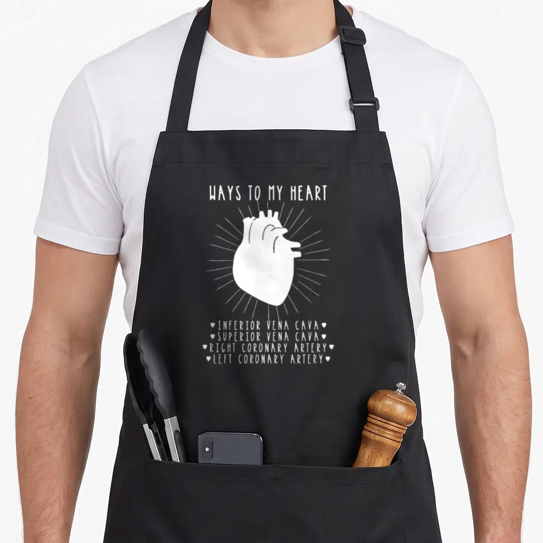 Cardiologist student aprons - White anatomical heart with Ways To My Heart text listing veins and arteries — shown on a black cotton canvas apron against a white background