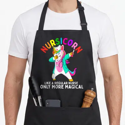 Unicorn nursing apron - Dabbing unicorn nurse in teal coat with Nursicorn rainbow text and white slogan — shown on a black cotton canvas apron against a white background